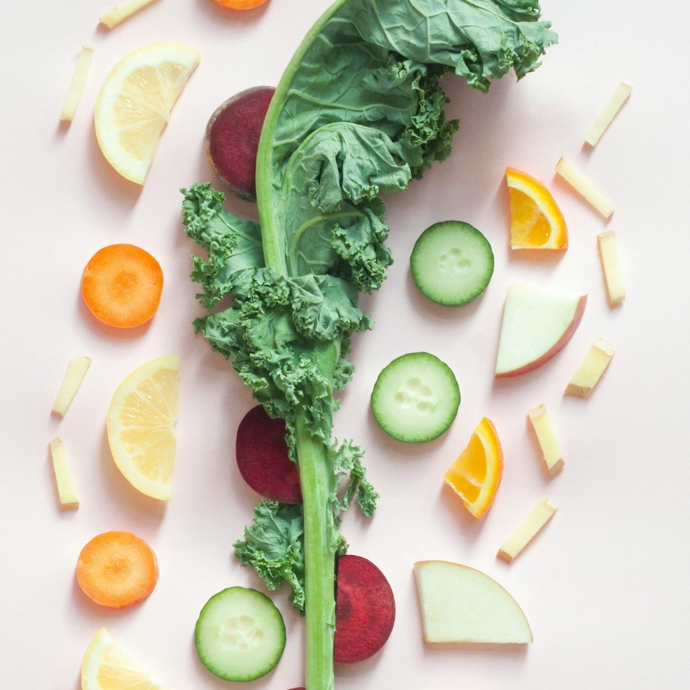 A variety of fresh fruits and vegetables arranged artistically on a light background.