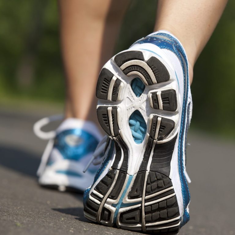 Close-up of the sole of a running shoe on a path, focusing on tread patterns.