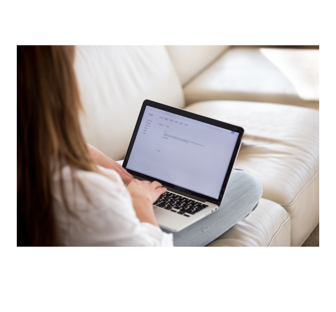 Person sitting on a sofa, typing on a laptop.