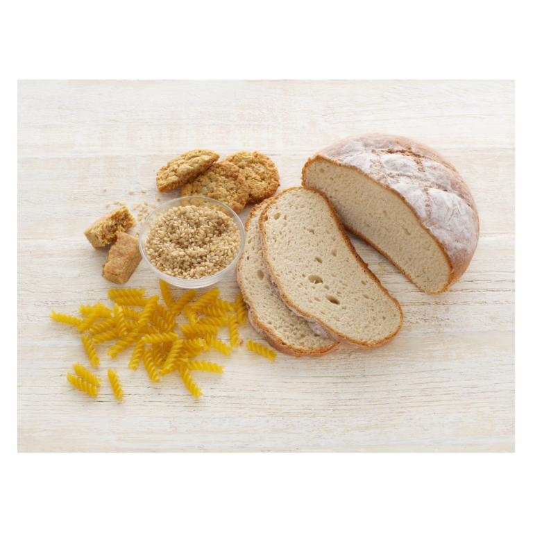 Loaf of bread, pasta, brown sugar, and cookies arranged on a wooden surface.
