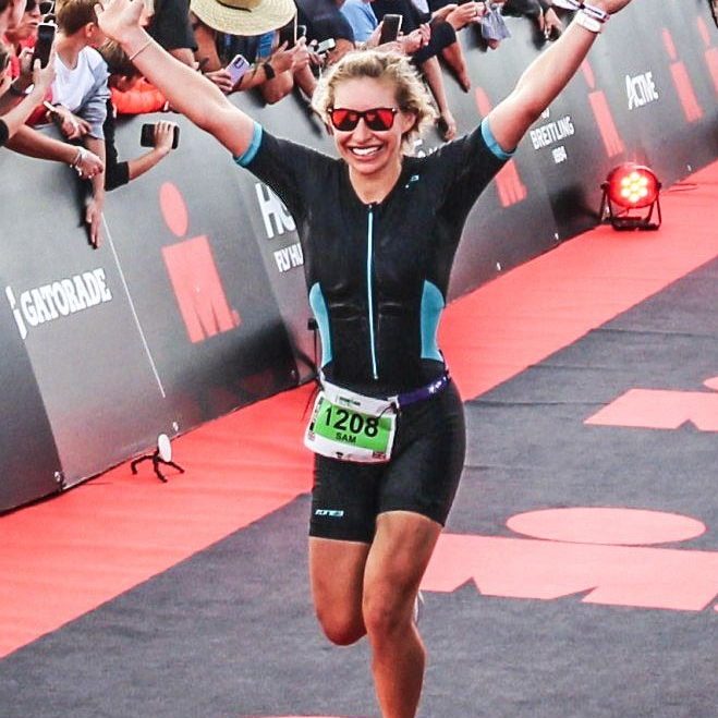 Athlete celebrating at the finish line of a triathlon event.